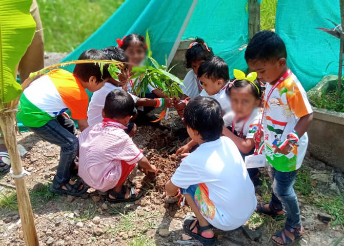Kindergartenkinder pflanzen junge Bäume